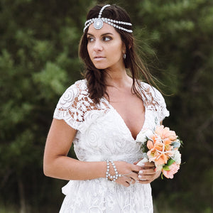Bride is holding wedding flowers and wearing a silver head chain
